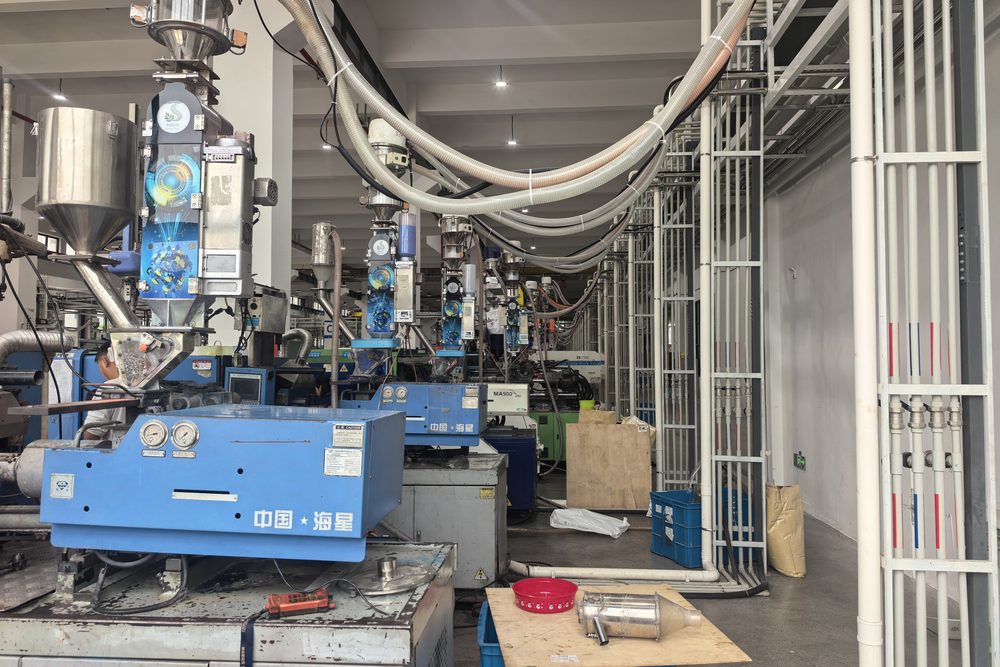 Bottle-cap moulding floor: dosing machines mounted at the hopper position, along a full row of presses