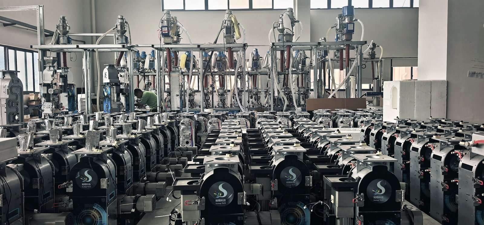 MegaColor assembly floor: completed units on test rigs, each connected to compressed air for run-in testing